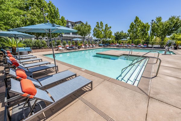 Relaxing poolside oasis at Montessa at Whitney Ranch Apartments with lounge chairs and lush landscaping