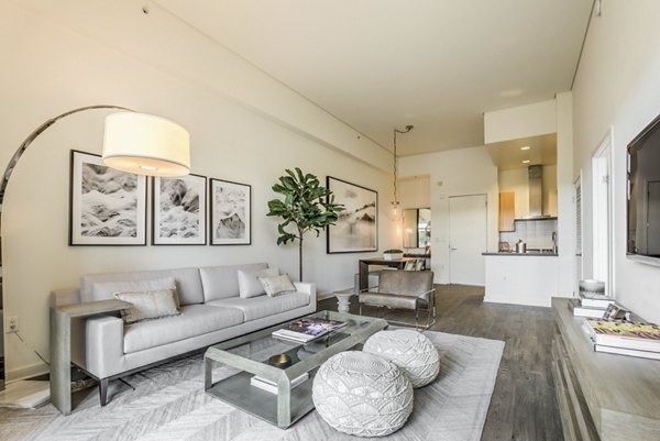 Spacious living room featuring modern furnishings and large windows at NoHo 14 Apartments