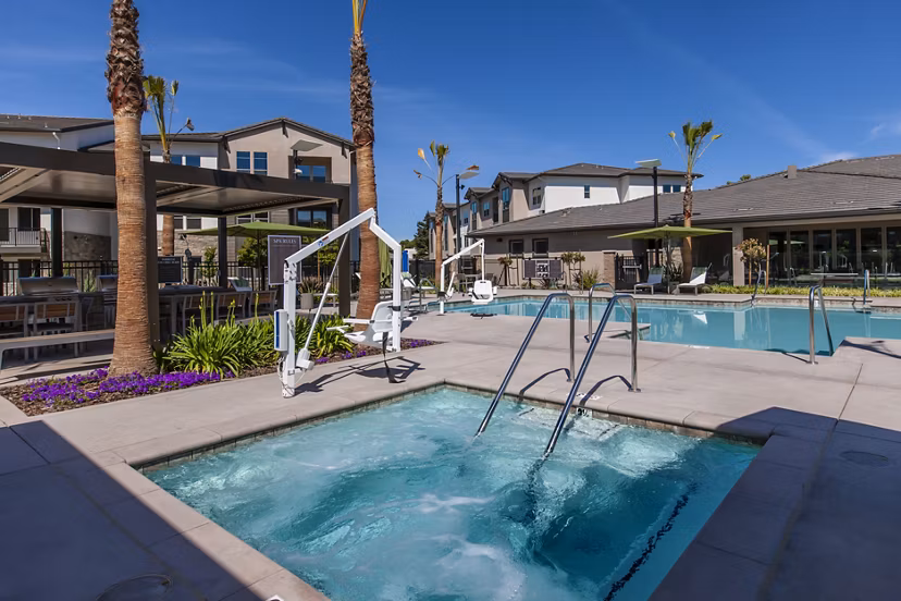 Resort-style pool with lounge chairs at Adega Apartments