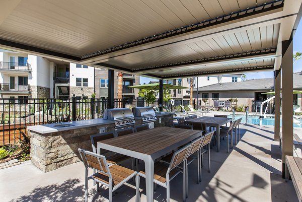 Outdoor grill area with modern seating at Adega Apartments, a luxury community managed by Greystar