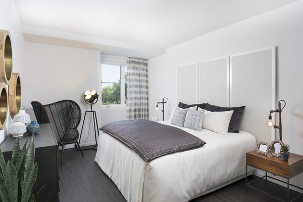 Elegant bedroom featuring designer furnishings and large windows at Garey Building Apartments in Los Angeles