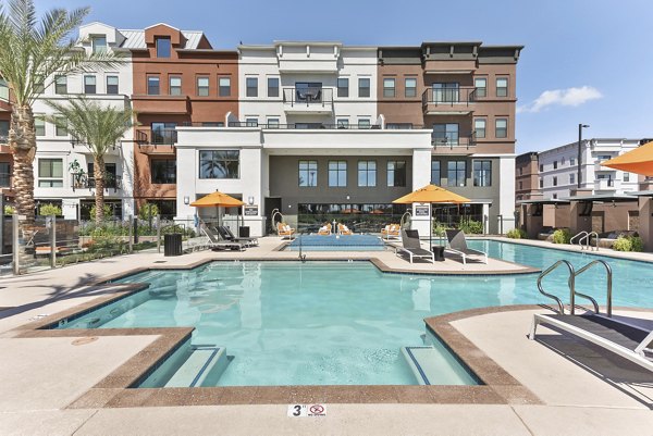 Resort-style pool at Summit at San Marcos Apartments featuring lounge chairs and lush landscaping