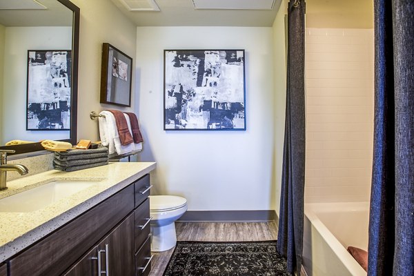 Bright bathroom with sleek fixtures and large mirror at Peak 16 Apartments, offering modern luxury living spaces