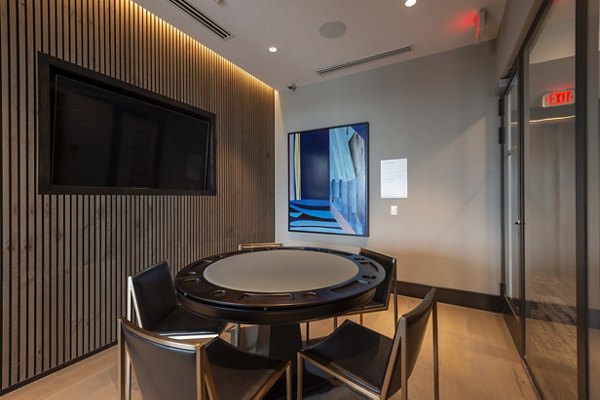 Meeting room featuring a round table, chairs, and wall-mounted TV with abstract art in luxury apartments