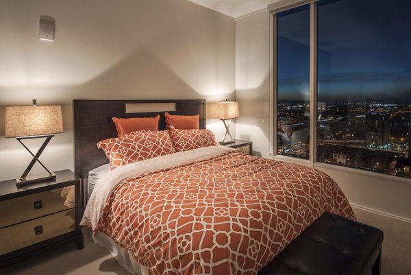 Cozy bedroom with large windows at One South Market Apartments featuring modern decor and luxurious furnishings