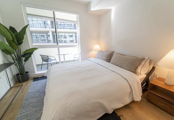 Luxurious bedroom featuring modern decor and large windows at The Upper Ivy Apartments