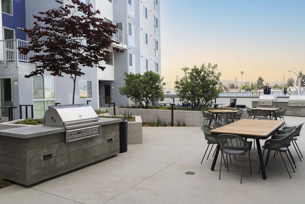 Outdoor grill area at The Upper Ivy Apartments with modern seating and scenic views, perfect for socializing and relaxation