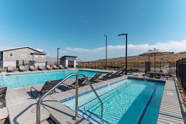 Sunlit outdoor pool at Haven Dell Apartments with surrounding greenery, offering a relaxing retreat for residents in a luxury setting