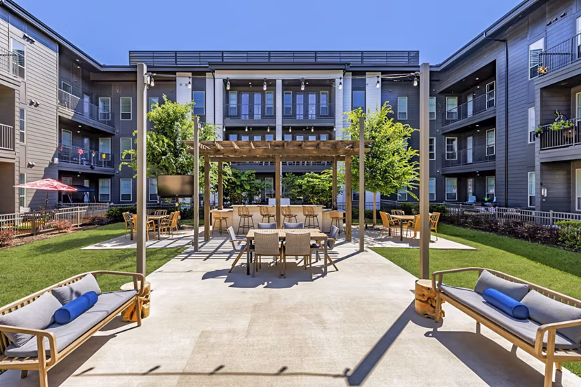 Grill area with seating on patio at Album Benbrook Apartments, offering a luxurious outdoor experience for residents