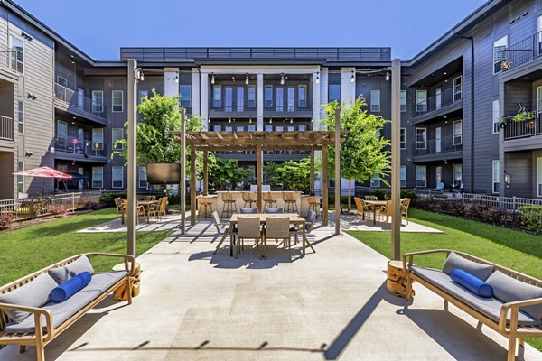 Grill area with seating on patio at Album Benbrook Apartments, offering a luxurious outdoor experience for residents