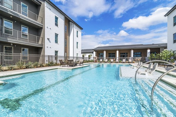 Lap pool surrounded by lounge chairs at Album Benbrook luxury apartments, ideal for relaxation and community gatherings