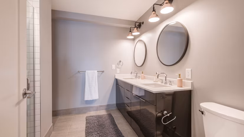 Modern bathroom with marble countertops and glass shower at Boston East Apartments