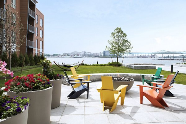 Cozy outdoor fire pit area at Boston East Apartments, perfect for gatherings and relaxation with a waterfront view
