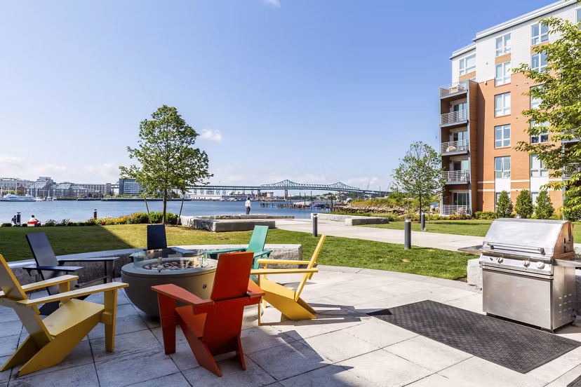 Outdoor grill area with modern seating at Boston East Apartments, offering a perfect space for social gatherings and relaxation by the waterfront