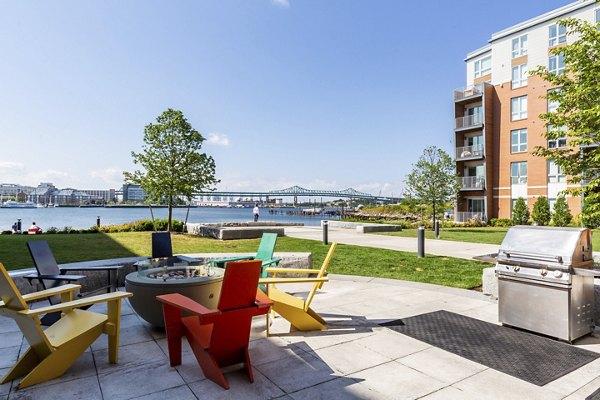 Outdoor grill area with modern seating at Boston East Apartments, offering a perfect space for social gatherings and relaxation by the waterfront