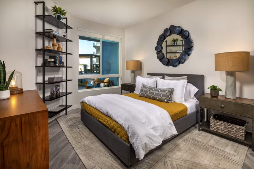 Cozy bedroom with modern decor at Garrison Apartments featuring plush bedding and ample natural light