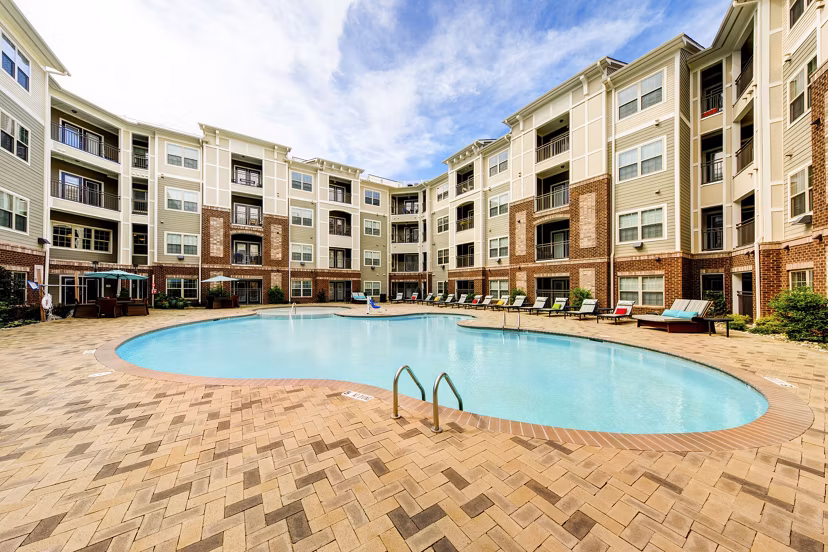 Pool area with elegant loungers and lush landscaping at The Manor at Weston Apartments, offering a luxury oasis for relaxation and recreation