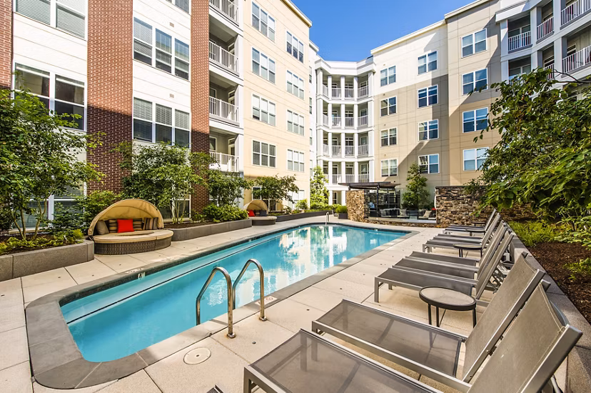 Resort-style pool at Pike3400 Apartments in luxury setting with lounge chairs and greenery