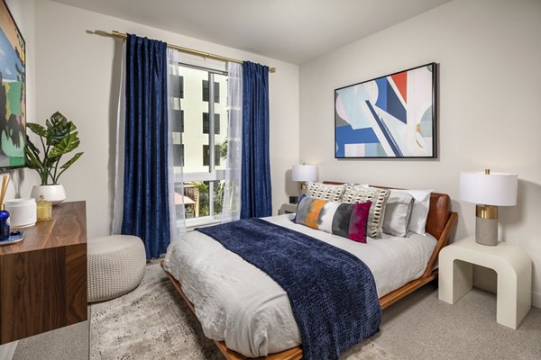 Cozy bedroom with modern decor at Cameo Apartments, featuring natural light and sleek furnishings for a luxurious living experience