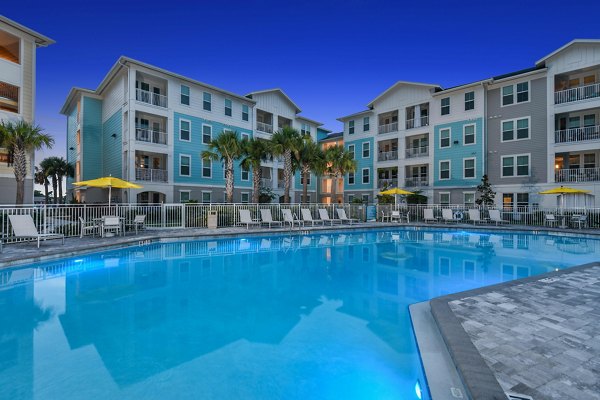 Expansive outdoor pool at Isla Apartments with lounge seating and lush landscaping