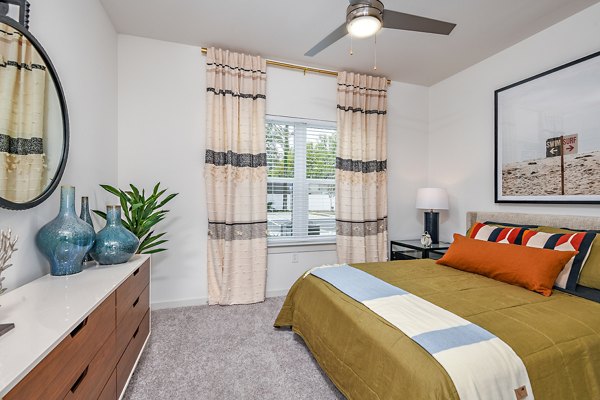 Modern bedroom with plush bedding at Renaissance Santa Rosa Apartments, featuring large windows and elegant decor