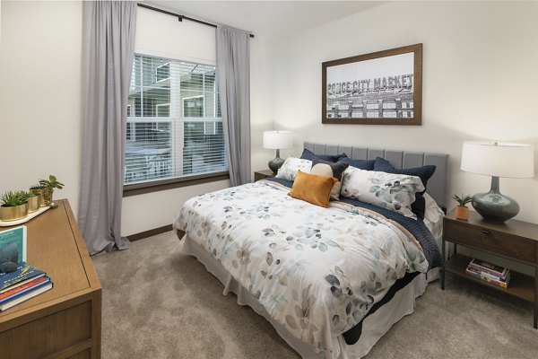 Cozy bedroom with plush carpet and large window at Everleigh Duluth Apartments, offering luxury living in a serene setting