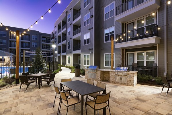 Outdoor grill area with modern seating and lush landscaping at Everleigh Duluth Apartments Perfect for gatherings and leisure activities