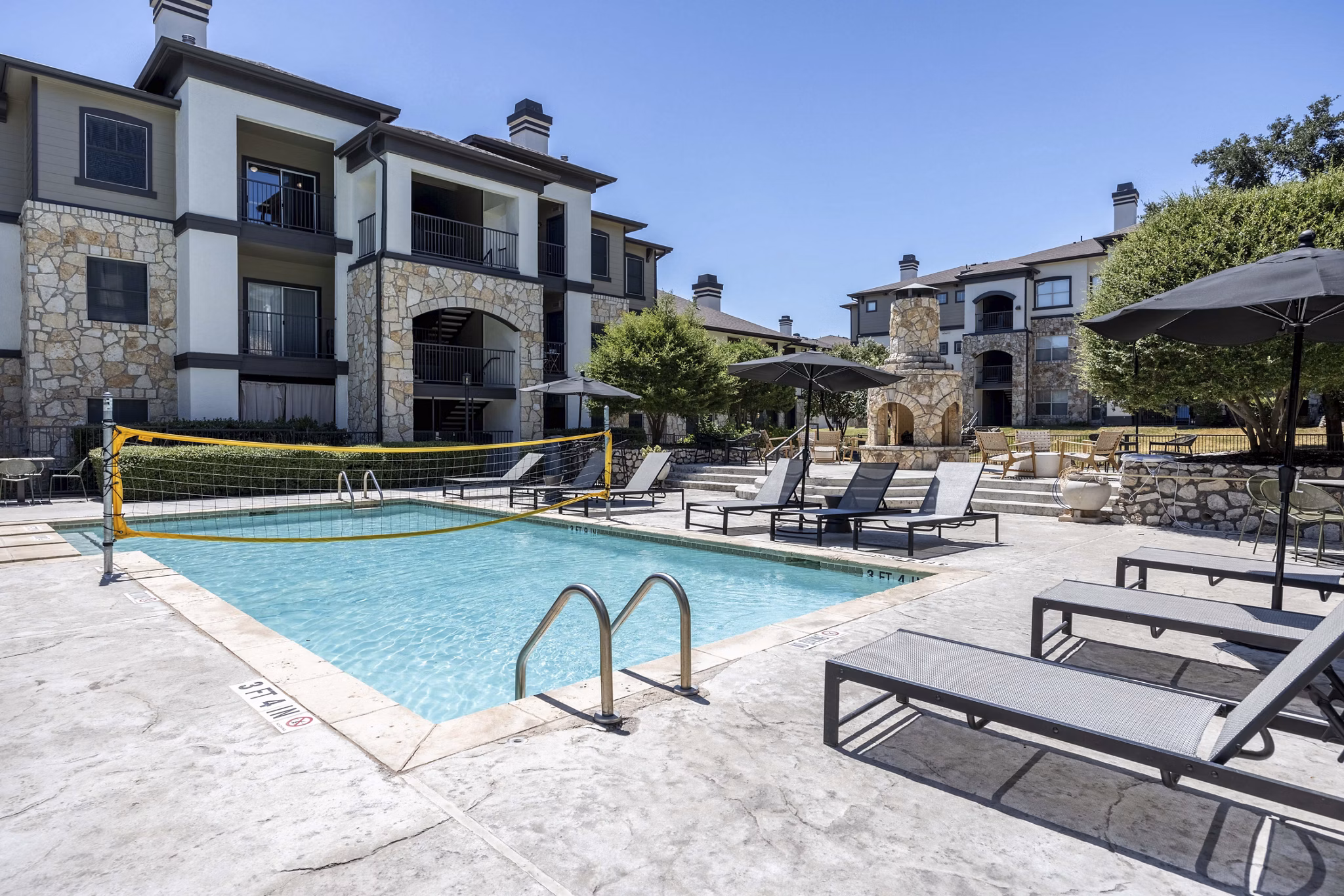 Pool area with lounge chairs and palm trees at Avana SoCo Apartments
