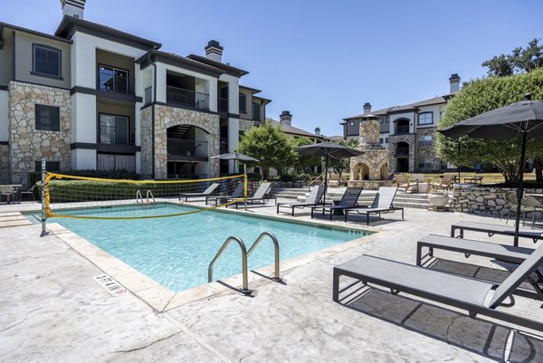 Pool area with lounge chairs and palm trees at Avana SoCo Apartments