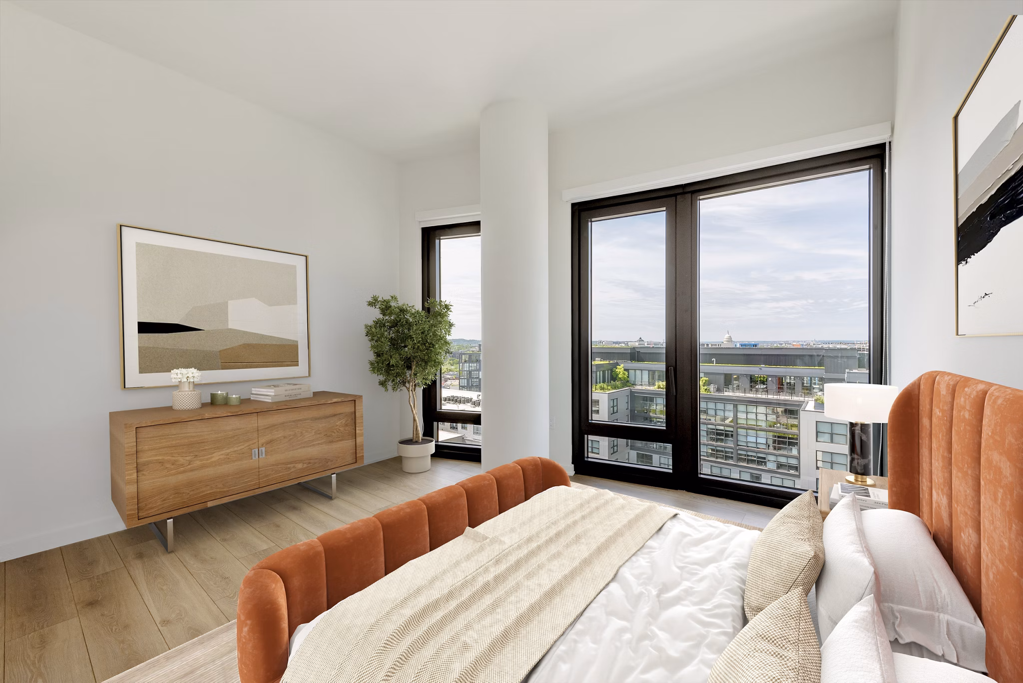 Modern bedroom featuring a bed, wooden dresser, plant, and large windows with city skyline views