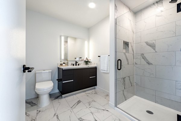 Modern bathroom featuring a spacious shower, sleek vanity, and mirror in luxury apartment