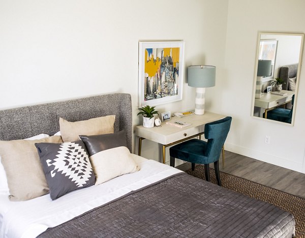 Cozy bedroom with chic decor at Mirella at Foxboro Apartments, featuring a stylish bed and ambient lighting