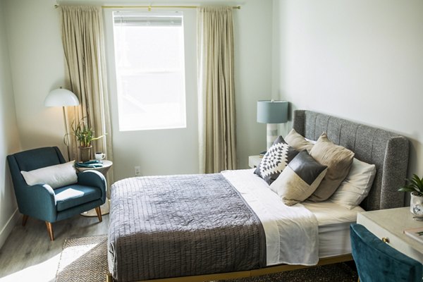 Bedroom with contemporary decor and large windows at Mirella at Foxboro Apartments