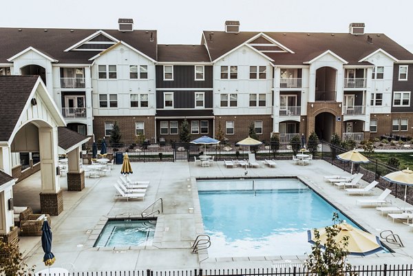 Luxury outdoor pool at Mirella at Foxboro Apartments with lounge seating and lush landscaping, perfect for relaxation and recreation