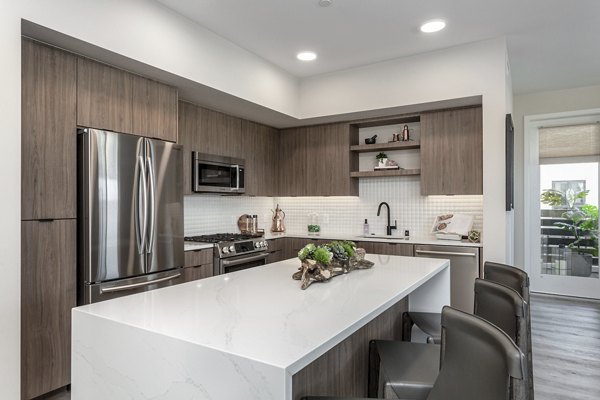Sleek kitchen with stainless steel appliances and quartz countertops in Prado West Apartments