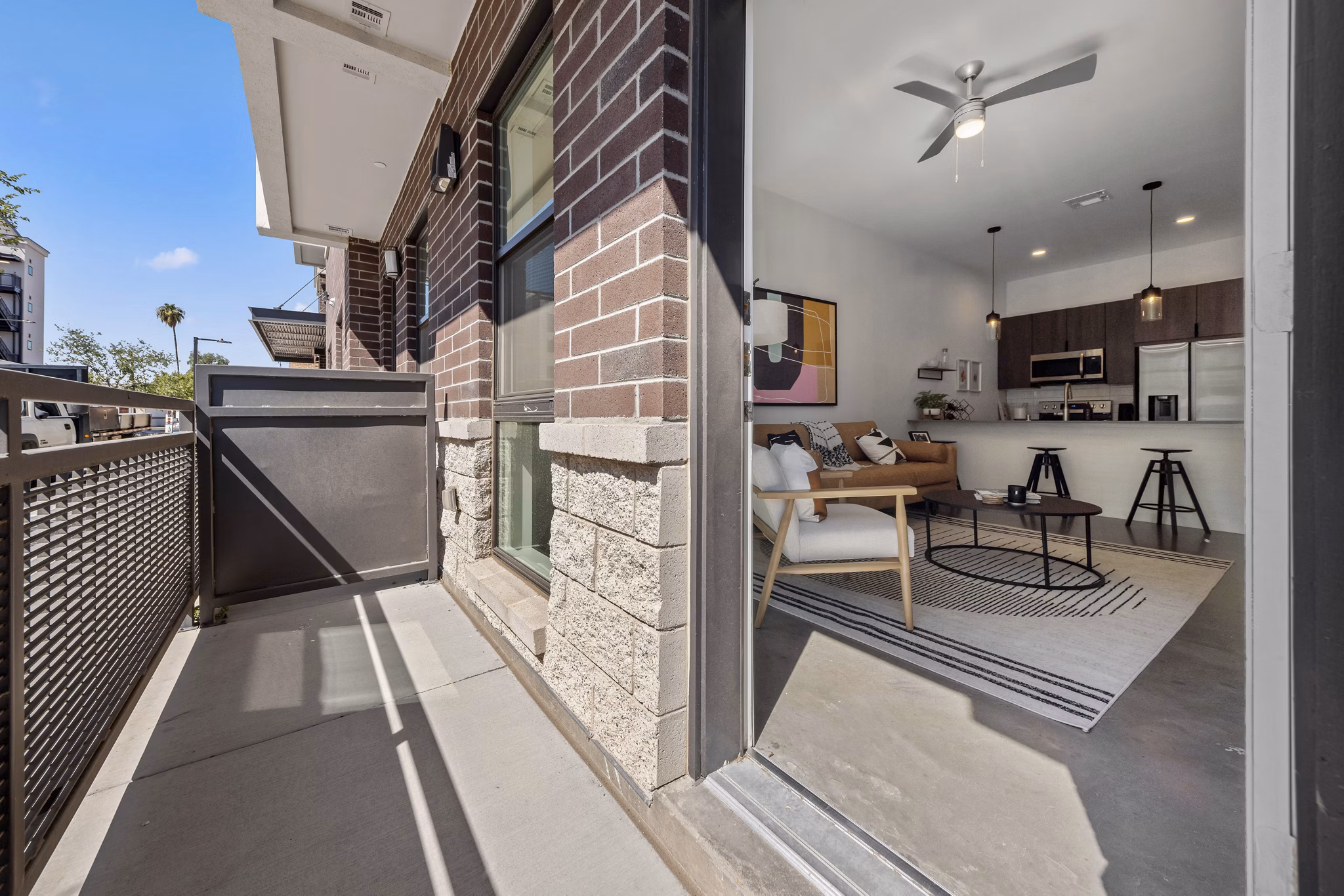 Sunny outdoor grill patio with modern furniture at The Battery Apartments, perfect for social gatherings and alfresco dining