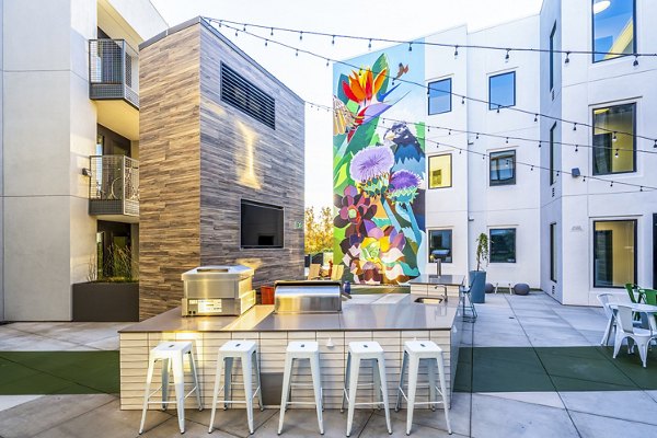 Grill area with modern patio furniture at Exhibit at J Town Apartments, perfect for outdoor gatherings and relaxation