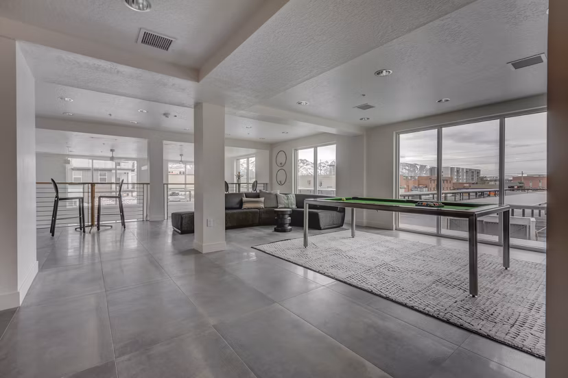 Game room with billiards table and lounge seating at Harmony3900 Apartments, offering residents a vibrant space for entertainment and relaxation