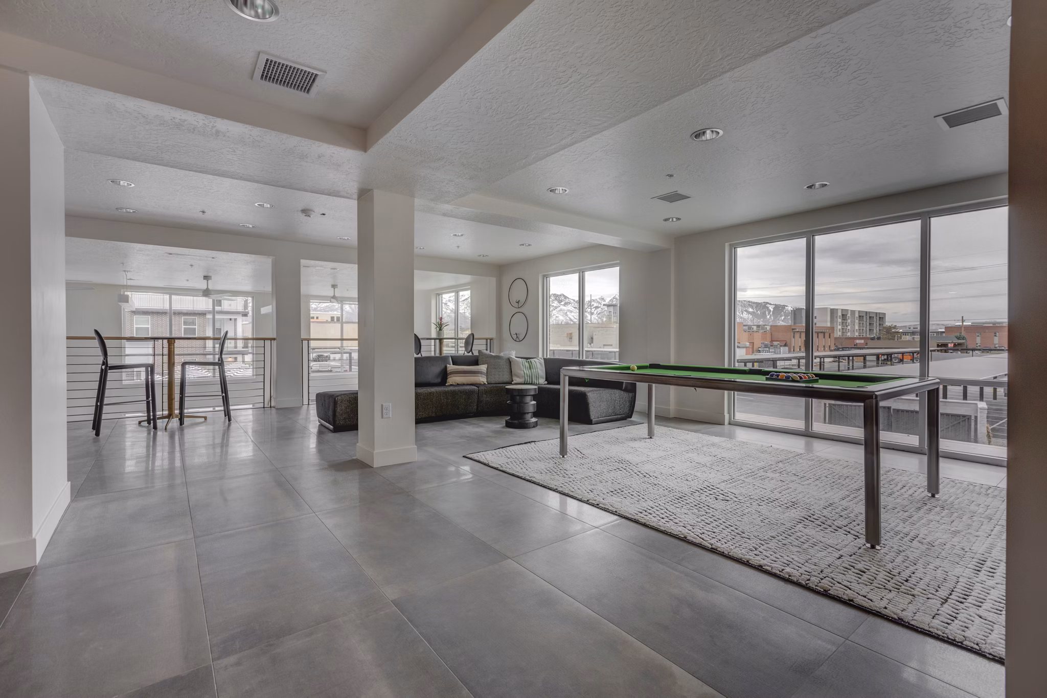 Game room with billiards table and lounge seating at Harmony3900 Apartments, offering residents a vibrant space for entertainment and relaxation