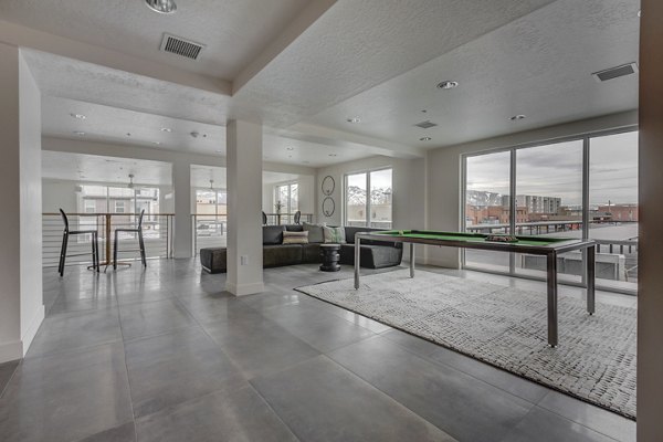 Game room with billiards table and lounge seating at Harmony3900 Apartments, offering residents a vibrant space for entertainment and relaxation