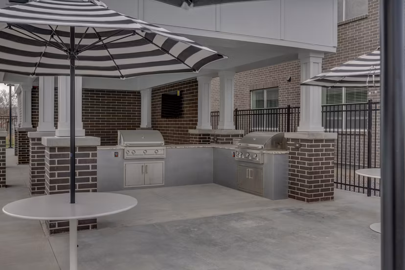 Outdoor grill area at Harmony3900 Apartments offers stylish seating and modern amenities for gatherings