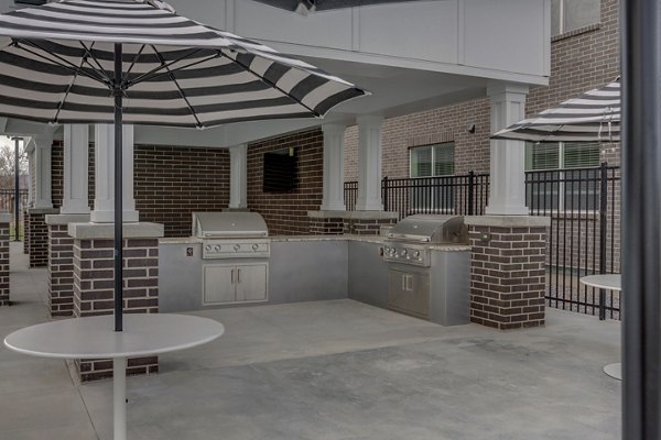 Outdoor grill area at Harmony3900 Apartments offers stylish seating and modern amenities for gatherings