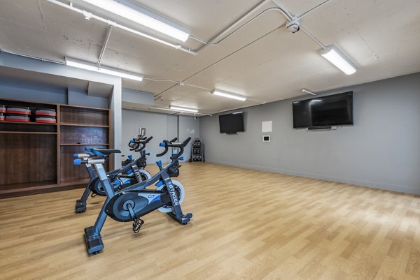 Yoga/spin studio with modern equipment at Brigham Apartments: Luxury fitness amenities in urban living environment
