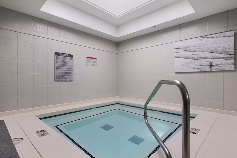 Modern outdoor pool at Brigham Apartments featuring stylish lounge chairs and lush landscaping