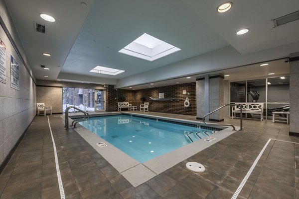 Modern outdoor pool at Brigham Apartments featuring stylish lounge chairs and lush landscaping