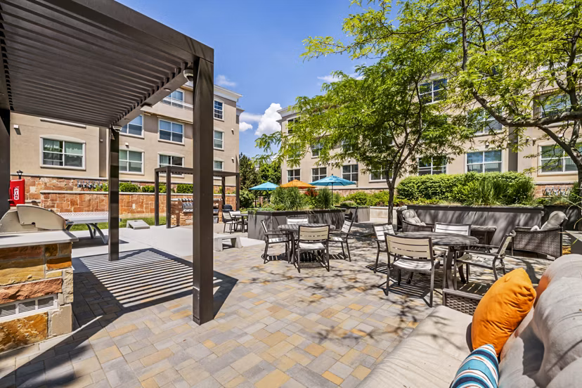 Grill area on patio with seating at Colonial Court Apartments, offering outdoor dining and relaxation space