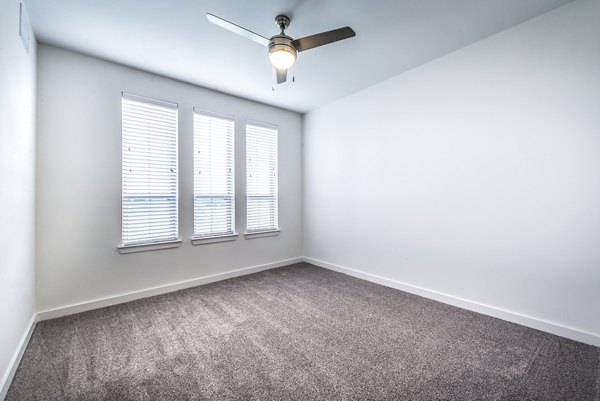 Cozy bedroom with modern dÃ©cor and large windows at The Holston Apartments, offering luxury living in a prime location