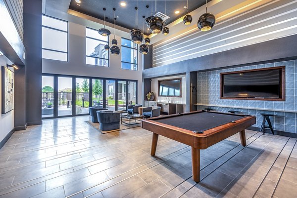 Modern game room featuring a pool table and seating area with large windows and a wall-mounted TV in luxury apartments