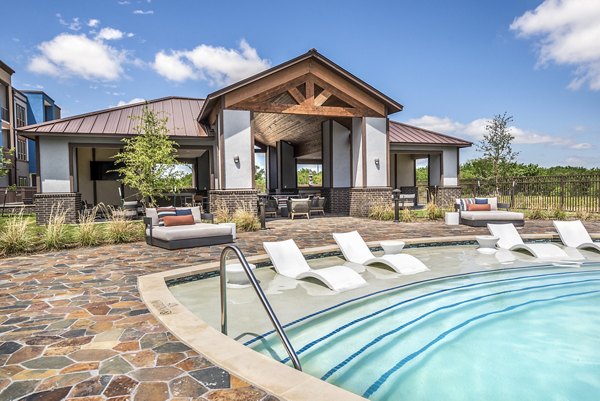 Resort-style outdoor pool at The Holston Apartments with lounge chairs and landscaped surroundings in vibrant community setting