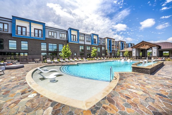 Resort-style pool with surrounding lounge area at The Holston Apartments, offering luxury living in a vibrant community setting